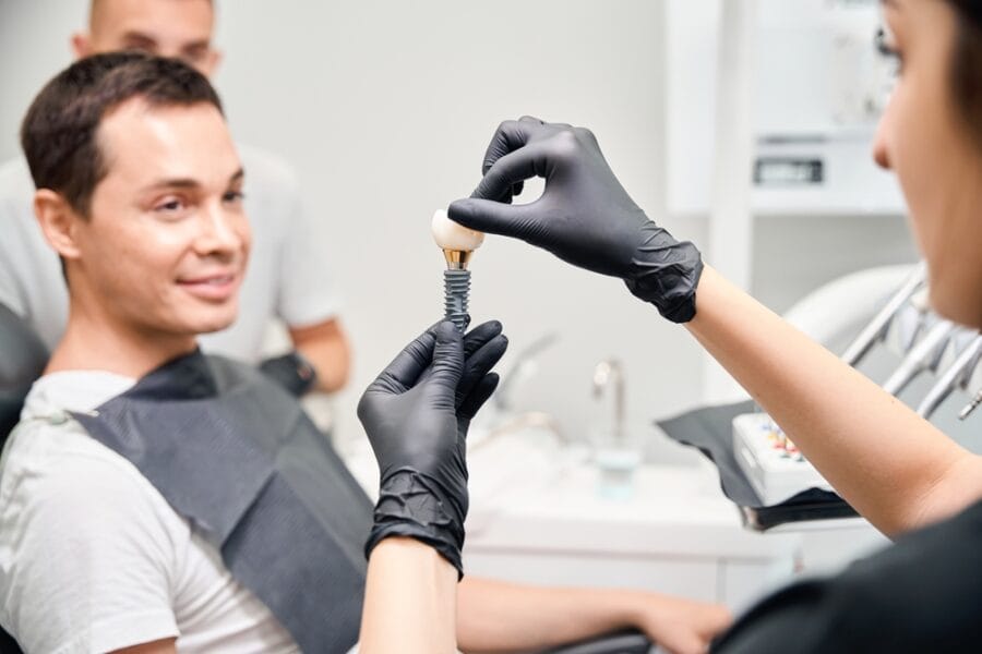 Aesthetic stomatology client watching at process of dental implant installation