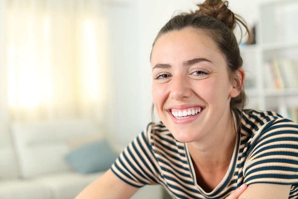 Beautiful perfect smile of a happy woman posing looking at camera at home