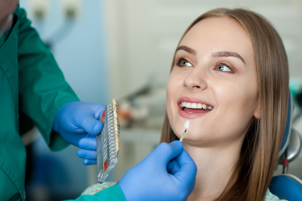 Dentist comparing tooth shades during a cosmetic dentistry consultation to achieve natural-looking results - Dentist in Nashville