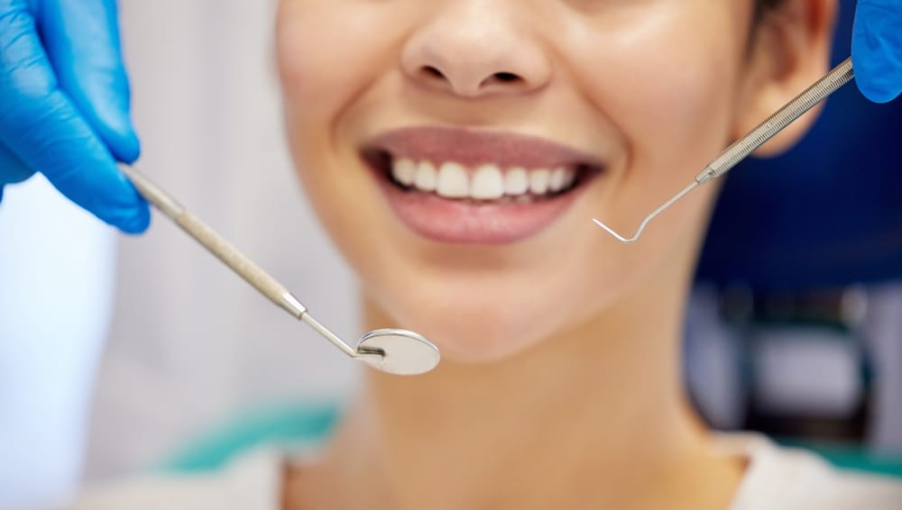 Hands, mirror and smile with woman at dentist for oral hygiene or dental care appointment closeup. Equipment, healthcare and medical with happy patient in chair at clinic for checkup or cleaning