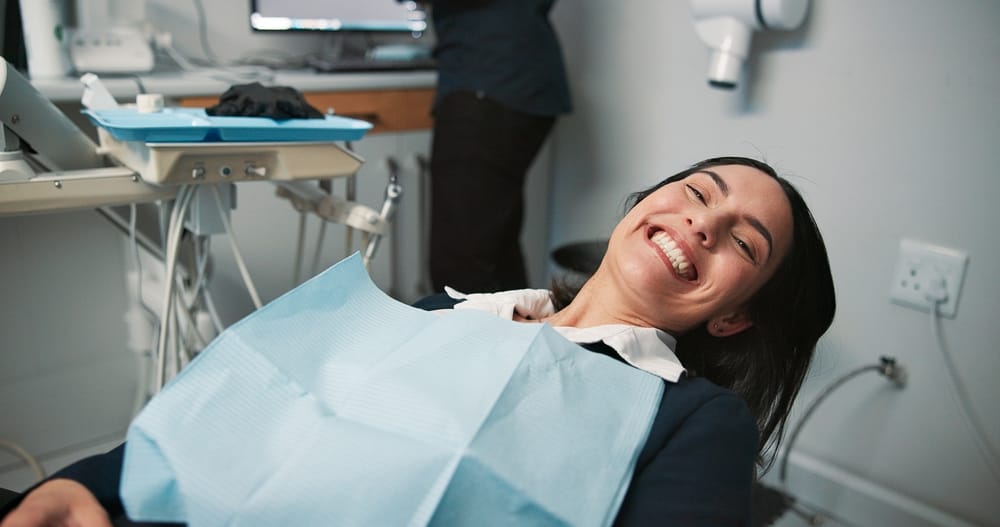 Happy woman, portrait or patient in dental clinic for checkup, veneers or medical procedure. Appointment, smile or person waiting in oral exam for dentistry, teeth whitening or cosmetics treatment