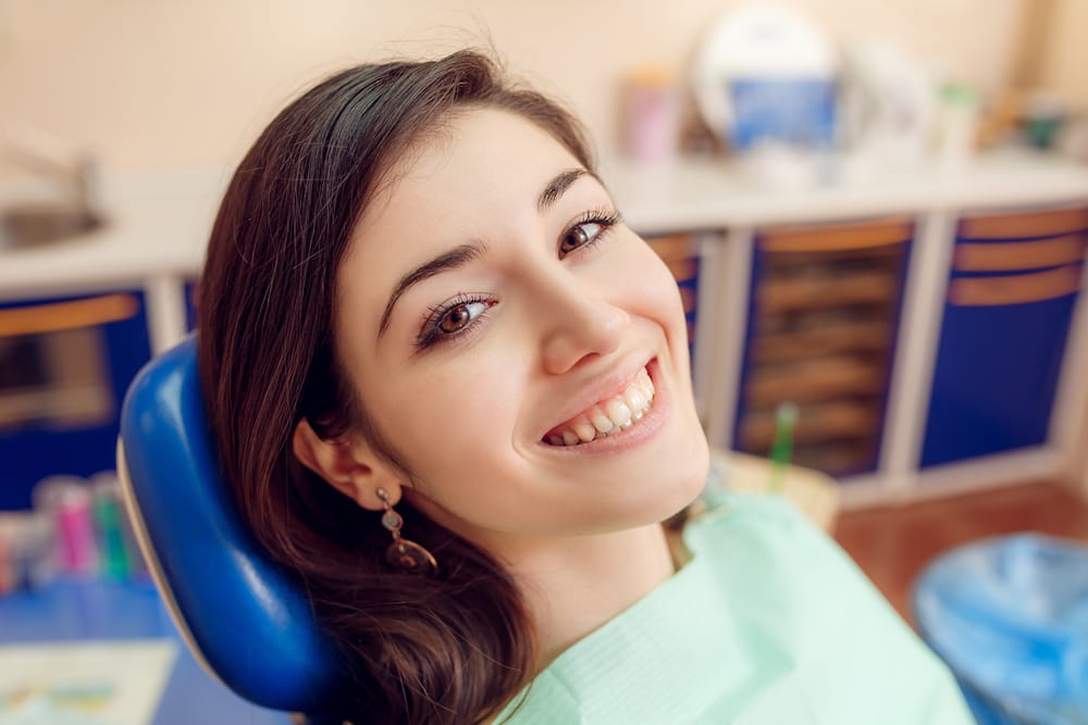 Smiling woman in a dental chair – Dental implants in Nashville Happy patient sitting in a dental chair after receiving professional dental care, showing a confident smile – Dental implants in Nashville