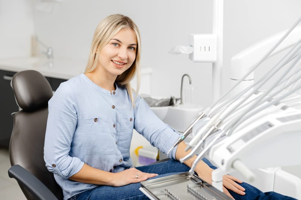 Young woman sitting on a dentist chair waiting for a dental checkup in a modern dental clinic