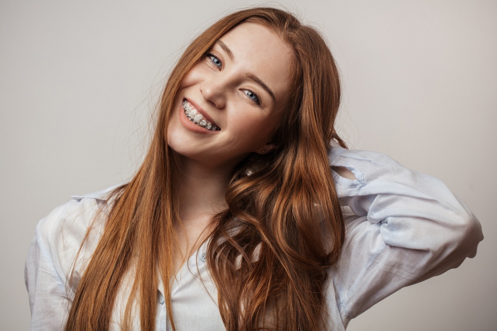 Young woman smiling confidently while wearing braces, highlighting successful orthodontic care and healthy teeth - Berry Hill Dentist