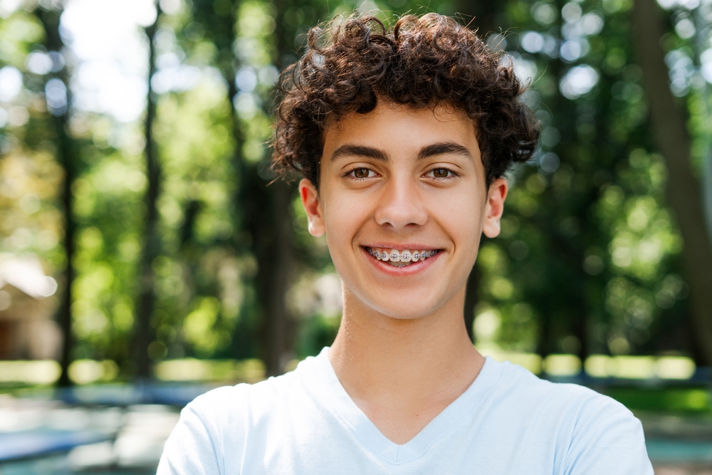 Teen smiling proudly with braces, representing positive orthodontic results and improved self-confidence - Berry Hill Dentist